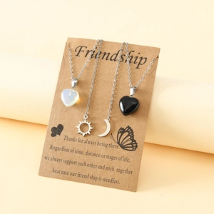 Detail view of sun and moon friendship necklaces with opal and onyx heart pendants on cards