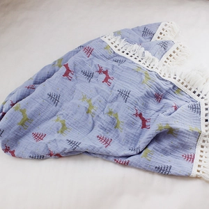 Detail of baby swaddle blanket featuring blue cotton muslin with festive reindeer print