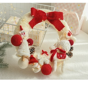 Close-up of wool felt Christmas wreath with reindeer, pine cones and warm LED lights