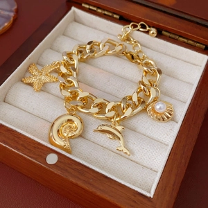 Detail of golden charm bracelet with starfish and pearls inside a dark wood jewelry box