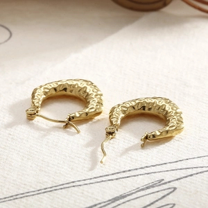 Detailed macro view of golden C-shaped hoop earrings with vintage hammered texture