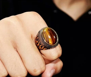 Detailed view of men's vintage tiger eye ring with flame pattern on bronze band
