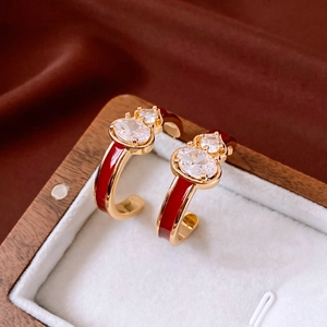 Macro view of C-shape hoop earring with red enamel and zircon gourd stud on silk