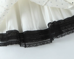 Close-up of white dress hem with blue polka dots and delicate black lace trim detail