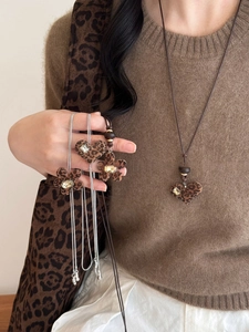 Close-up of leopard print heart and flower pendants with clear crystals on a brown cord