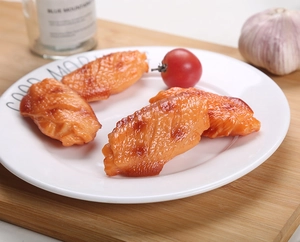 Close-up of realistic roasted chicken wing models on a plate with food props