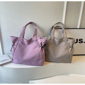 Detail of minimalist tote bags in lavender and khaki with side drawstring design