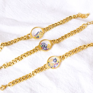 Gold chain bracelets with evil eye and hamsa charms featuring colorful crystals
