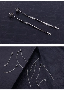 Detailed macro view of silver stainless steel chain tassel earrings on dark leather background