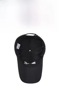 Detail showing the 100% cotton material tag and internal stitching of the black baseball cap
