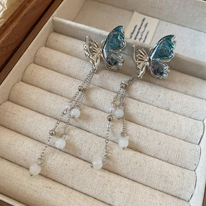 Détails de boucles d'oreilles papillon argentées avec ailes bleues et pompons de perles