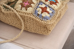 Macro detail of hand-woven straw bag with colorful crochet floral granny square patterns