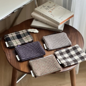 Close-up of five checkered wool mini pouches with zippers and simple wish woven labels