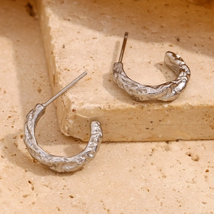 Dettaglio macro di orecchini a C in argento con una trama di lava martellata unica