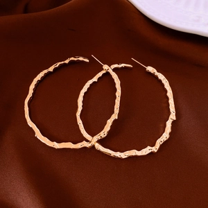 Close-up of gold plated round earrings with irregular hammer texture on brown silk