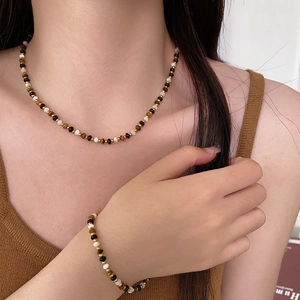 Natural tiger eye stone beaded necklace and bracelet set worn by a model in warm lighting