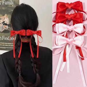 Detail of sweet satin ribbon hair clips with heart accents in red and pink colors