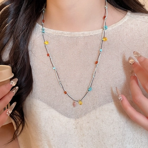 Close-up of bohemian multi-layered woven rope necklace with colorful stone beads on a model