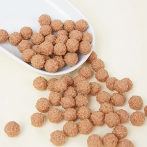 Realistic miniature meatballs food model with textured surface in a white ceramic plate