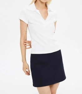 Detail view of a white short-sleeved polo shirt and navy blue skirt on a white background