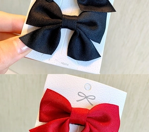 Close-up of black and red ribbed ribbon bow hair clips on product display cards
