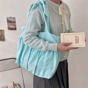 Detailed texture of light blue pleated canvas tote bag with soft bow-knot shoulder strap