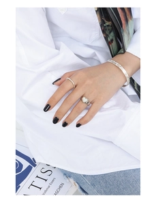 Detail view of silver heart ring and matching bangle set worn with a white shirt