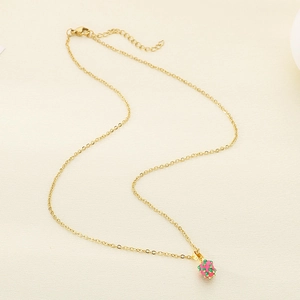 Macro detail of gold stainless steel necklace with pink strawberry enamel pendant