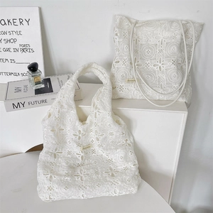 Close-up of white floral embroidery lace texture and Sorakka brand label on a tote bag