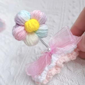 Macro shot of handcrafted crochet flower hair clip with pink ribbon and faux pearl detail