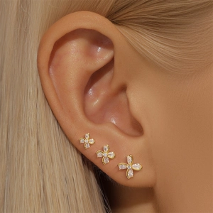 Close-up of three graduated gold floral earrings with sparkling cubic zirconia on model