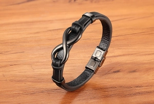 Detail of black leather bracelet with black infinity symbol and stainless steel clasp