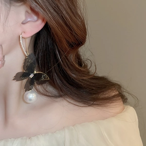 Detail of mesh butterfly earrings with sparkling diamonds and elegant white pearls