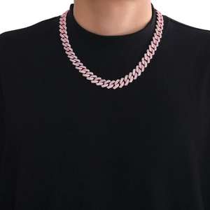 Detailed view of pink iced-out Cuban link chain worn by male model on black background