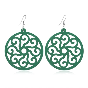Detail view of green circular hollow wooden earrings with silver hooks on white background