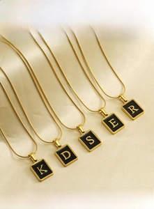 Gros plan de pendentifs lettres en acier inoxydable plaqué or 18 carats sur chaînes