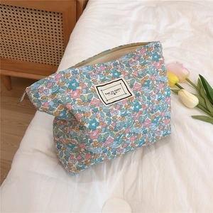 Detail of floral makeup bag with blue and pink patterns on white linen background