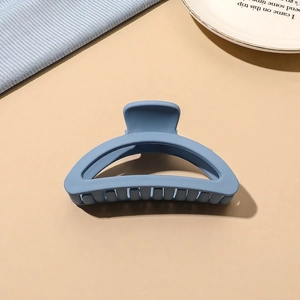 Close-up of a matte blue hair claw clip with a sleek half-moon design and sturdy teeth