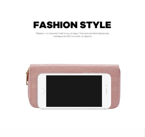 Pink embossed crocodile pattern long wallet with gold zipper compared to a phone