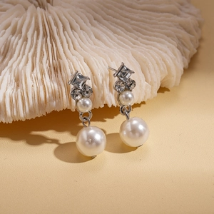 Détail de boucles d'oreilles en argent avec perles et cristaux sur support de corail