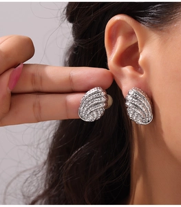 Gros plan de boucles d'oreilles géométriques en argent avec texture martelée et éclat