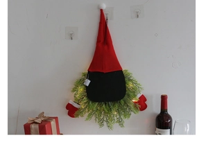 Detail of LED glowing Christmas gnome wreath with artificial pine branches and knitted fabric