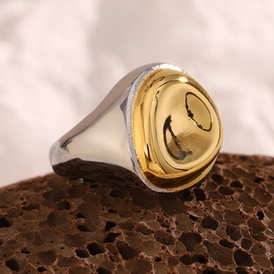 Detailed macro shot of a two-tone 18K gold-plated stainless steel signet ring on volcanic rock