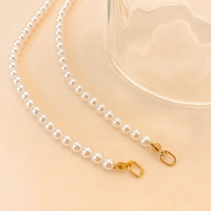 Detailed macro view of smooth white pearls with a polished gold metal clasp attachment