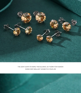 Macro shot of 925 sterling silver stud earrings with golden cubic zirconia on velvet