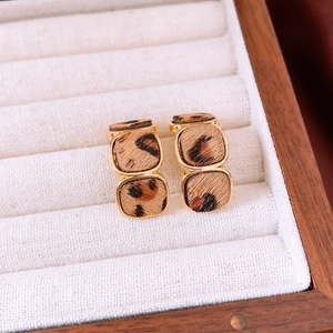 Macro shot of gold-plated leopard print stud earrings with horsehair texture detail