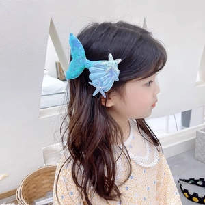 Detail of sequin mermaid tail hair clip with shell and starfish on a child model