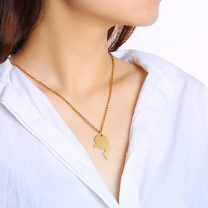 Detail of a golden puzzle-shaped necklace pendant worn by a model on a white background