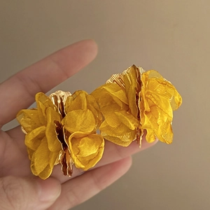 Detail of yellow tulle flower earrings with multilayered petals and gold pistil center