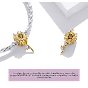 Macro view of gold sunflower charm with black gems on a silver snake chain bracelet
